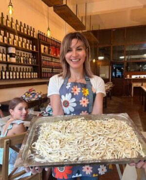 local food tour guide and passta cooking class host proudely holidng plate of hand made pasta