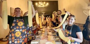 Guests stretching fresh pasta during an authentic cooking class experience in Italy