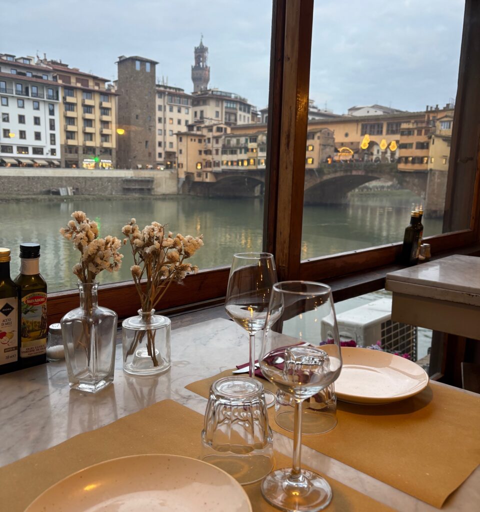 Traditional restaurant table overlooking Arno River during authentic Florence food tour experience