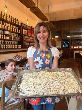 local food tour guide and passta cooking class host proudely holidng plate of hand made pasta