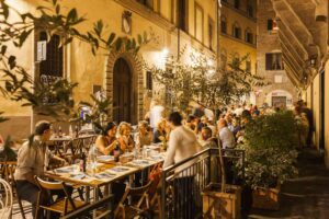 Locals dinin outdoors in Oltrarno district during authentic Florence food tour experience
